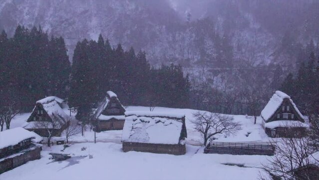 Snow slowly falling on traditional mountain village at dawn