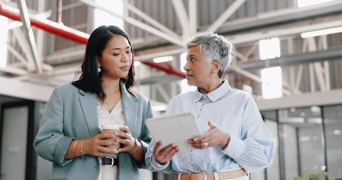 Business, tablet and senior woman with employee, talking and walking in modern office. Women, female administrator and manager speaking, conversation for schedule and leader in workplace or corporate