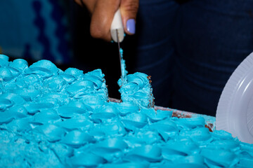 Cutting and separating piece of cake with blue icing.