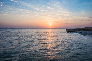 Fototapeta premium Beautiful sunrise at sea. Dawn on the Red Sea. The sun is reflected in the sea. Light clouds in the blue dawn sky. Tropical sunrise.