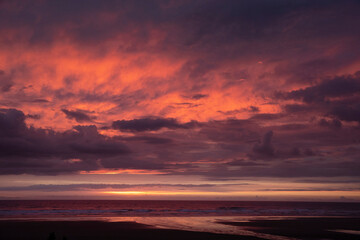 Naklejka na ściany i meble Sunset at beach and coast of Glinks Gully, kust, new zealand. Red skies.