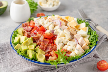 Tradition Cobb salad with fried chicken, avocado, fresh tomatoes, eggs, bacon and cheese on a...