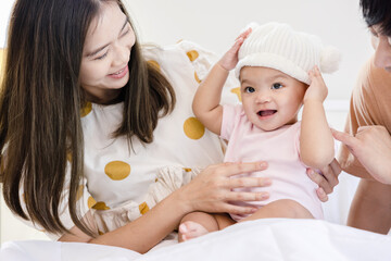 Toddlers are feeling safe and happy with their parents' care in bed at home. Asian family takes care of their children's health with love. Young children are learning to develop their brains.