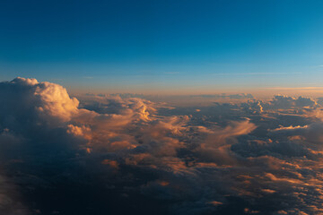 Natural background of sky, sunset above dark clouds, view through window from inside of airplane during the flight.