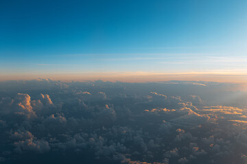 Natural background of sky, sunset above dark clouds, view from inside of airplane during the flight.