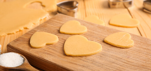Fototapeta na wymiar Board with raw heart shaped cookies on table, closeup. Valentines Day celebration