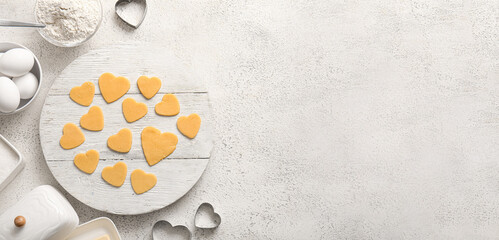 Board with raw heart shaped cookies and ingredients on light background with space for text....