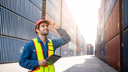 Engineer or foreman checking inventory or task details at container yard warehouse while wearing...