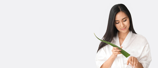 Beautiful Asian woman holding aloe vera on white background with space for text