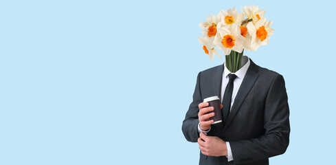 Young businessman with bouquet of flowers instead of his head and cup of coffee on light blue...
