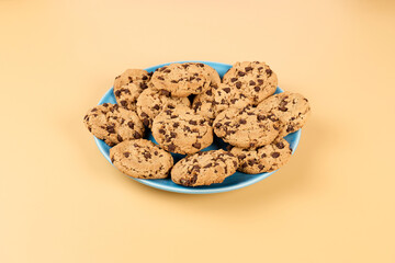 Plate of chocolate cookies isolated on a yellow background, close up