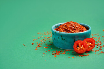 Bowl of chipotle chili flakes on green background