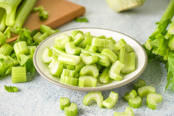 Plate with fresh cut celery on light background, closeup