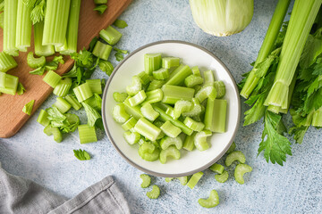 Plate with fresh cut celery on light background
