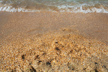 a small wave finds on the sea sand.