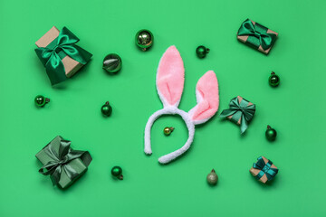 Bunny ears with Christmas balls and gifts on green background
