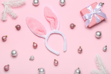 Bunny ears with Christmas balls, fir branches and gift on pink background