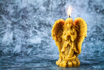 Beeswax praying angel candle on stone background