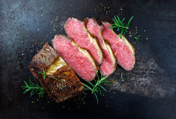 Traditional Commonwealth Sunday roast beef sliced with herbs and served as top view on a rustic...