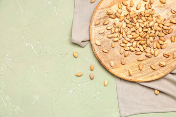 Napkin and board with tasty pistachio nuts on grey background
