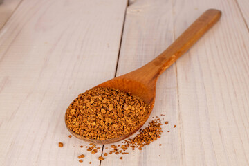 Fragrant instant coffee with a wooden spoon on a wooden table, macro.