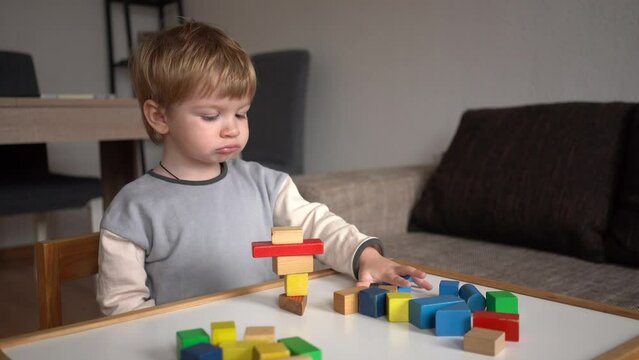 little boy playing with wooden multi-colored cubes