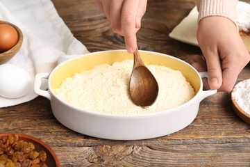 Woman preparing cheese pie on wooden table