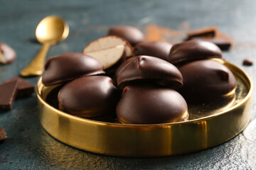 Metallic board with sweet chocolate bird's milk candies on dark background, closeup