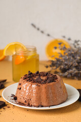 Plate with delicious pudding, chocolate and lemonade on beige table near grey wall