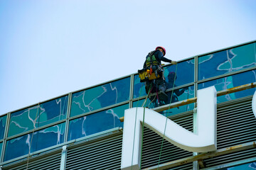 an industrial climber descends from the roof of a building