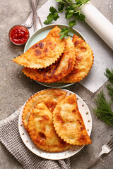 Plates with tasty chebureks and sauce on grunge background