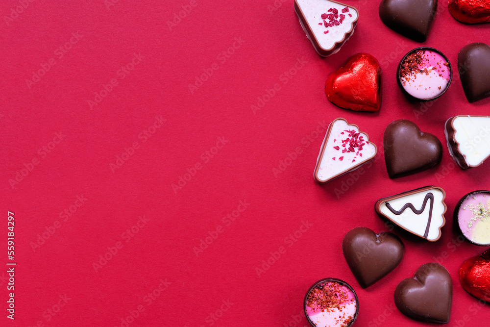 Poster Valentines Day chocolate side border. Red and pink heart theme. Above view on a red paper background with copy space.