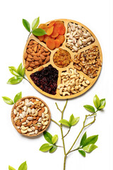 Dried fruits and nuts mixed on wooden plates, branch with young green leaves. Concept of the Jewish holiday Tu Bishvat on white background