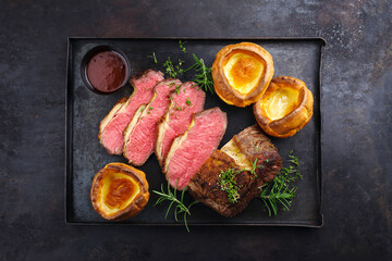 Traditional Commonwealth Sunday roast beef sliced with Yorkshire pudding and red wine sauce served...