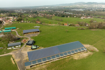 Aerial view of blue photovoltaic solar panels mounted on farm building roof for producing clean ecological electricity. Production of renewable energy concept