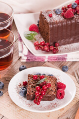 Chocolate sponge cake with fresh fruit on white dish.