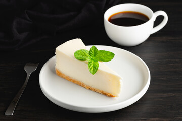 Cheesecake and cup of black coffee on a wooden table. Tasty snack or coffee time with slice of cake
