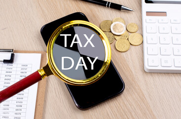 TAX DAY text on the magnifier with smartphone, calculator and coins