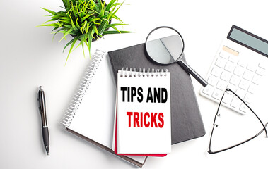 TIPS AND TRICKS text on notebook on white wooden background , business concept