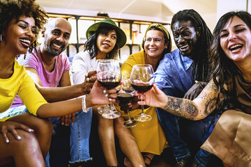 Joyful multi-ethnic group of adult friends having fun celebrating with red wine
