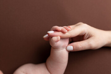 Close-up little hand of child and palm of mother and father. The newborn baby has a firm grip on the parent's finger after birth. A newborn holds on to mom's, dad's finger. - obrazy, fototapety, plakaty