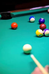 Foto op Plexiglas Playing billiards on a green table. A close-up of a billiard ball that the player is aiming at. © Marina Gordejeva