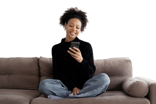 The curly-haired woman smiles uses the phone writes sms makes an online order sits on the couch, transparent background.
