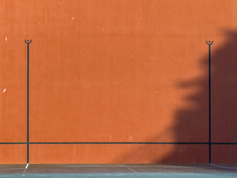 red wall of a Basque pelota fronton in France. with the black stripes drawn.