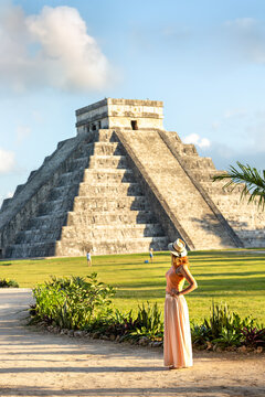 A tourist girl in a hat looks at the pyramid of Kukulcan in Chichen Itza. Mayan pyramids in Yucatan, Mexico