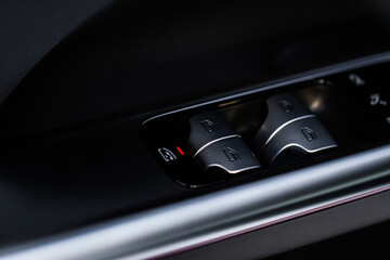 Close up view of button controlling window in modern car interior. Vehicle interior detail. Door handle with windows controls