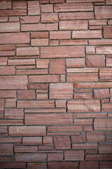 Thinly layered sandstone bricks in a wall with gray grout