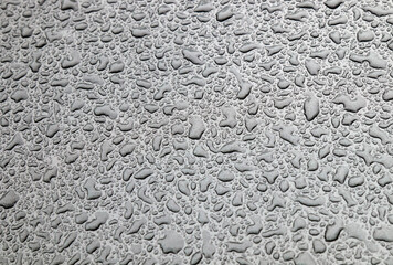 Dusty drops of water on the glass and hood of a car