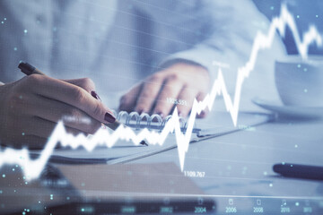 Double exposure of woman's hands making notes with forex graph hologram. Concept technical analysis.