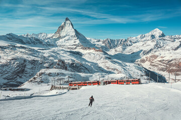 Matterhorn, Switzerland, Winter tourist train and male skier skiing with Matterhorn mountain in the...